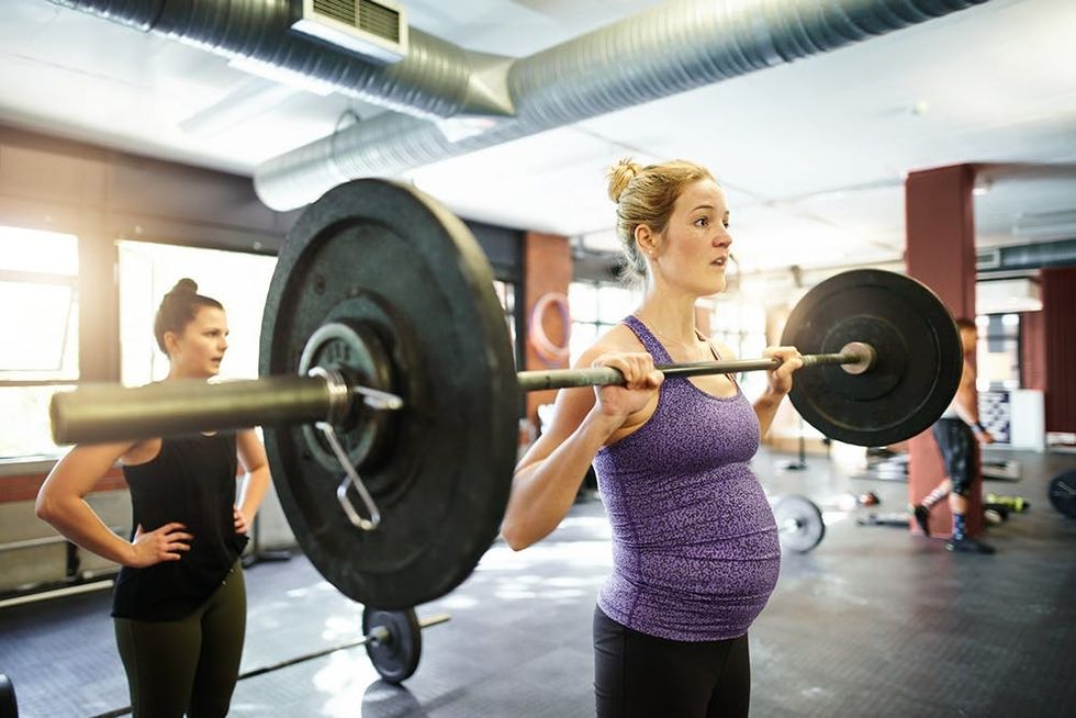 Shot of a pregnant young woman working out with a barbell at a gym