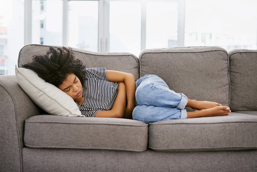 Shot of a young woman experiencing stomach pain on the sofa at home