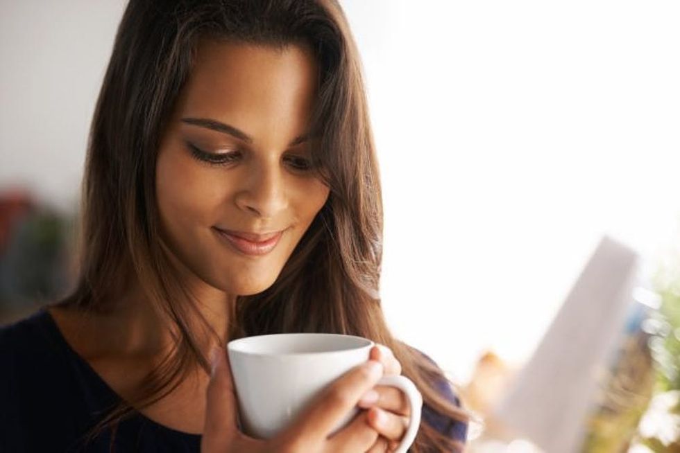 Shot of an attractive young woman drinking a coffee at home
