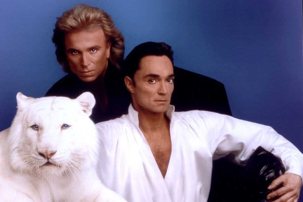 Siegfried and Roy with a white tiger against a blue background