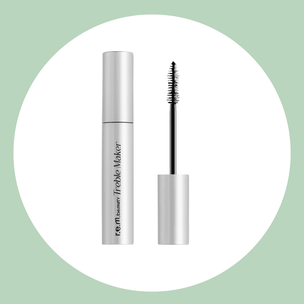 Silver mascara tube and wand on a pastel green background.