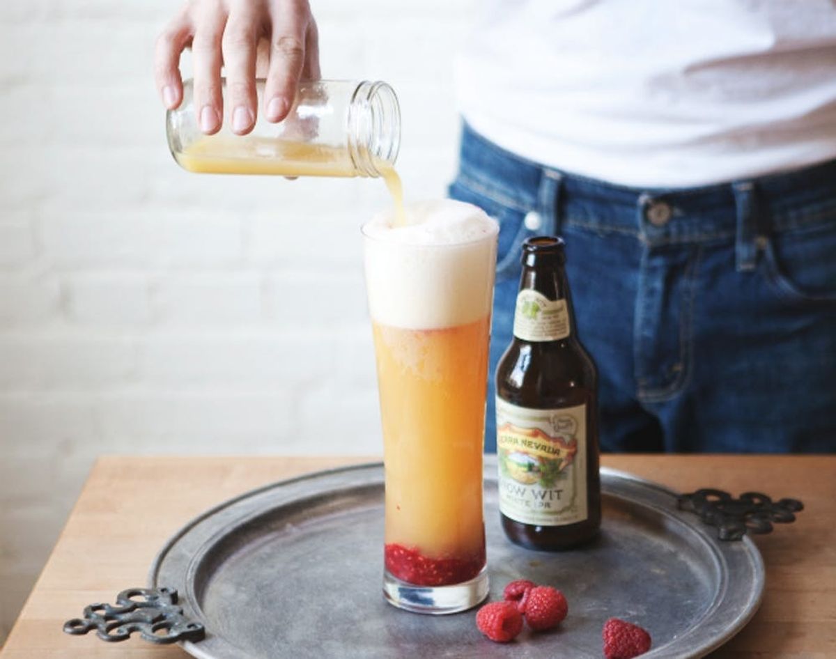 Silver platter holds a beer cocktail with wit beer and raspberries