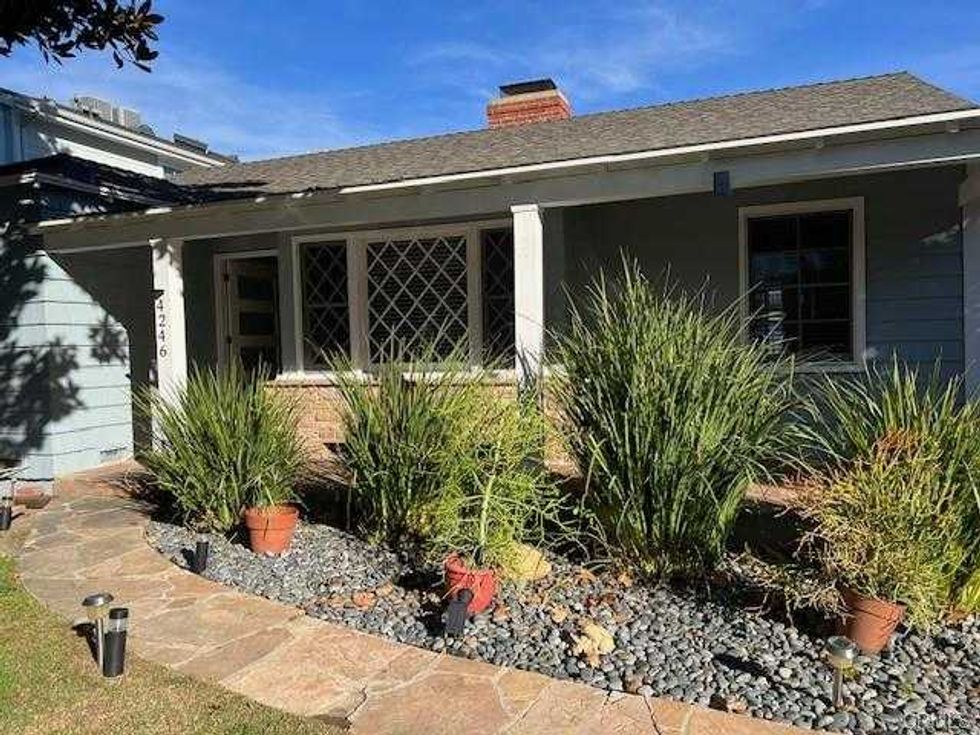 Single-story house with a stone pathway, porch, and landscaped garden.