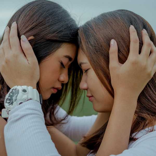 sisters leaning their heads together in a serious moment