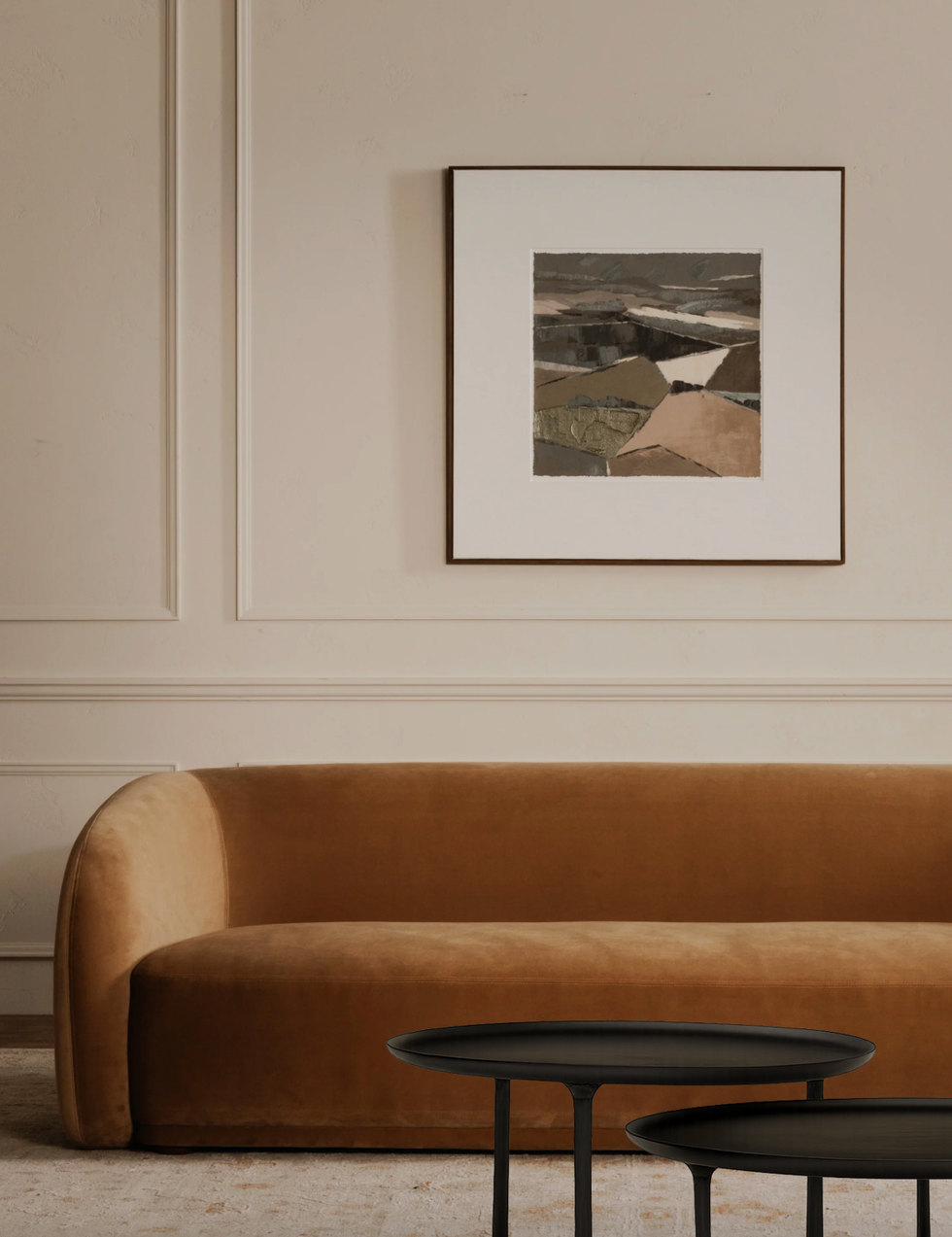 Sleek modern living room with brown sofa, abstract art, and round black tables.