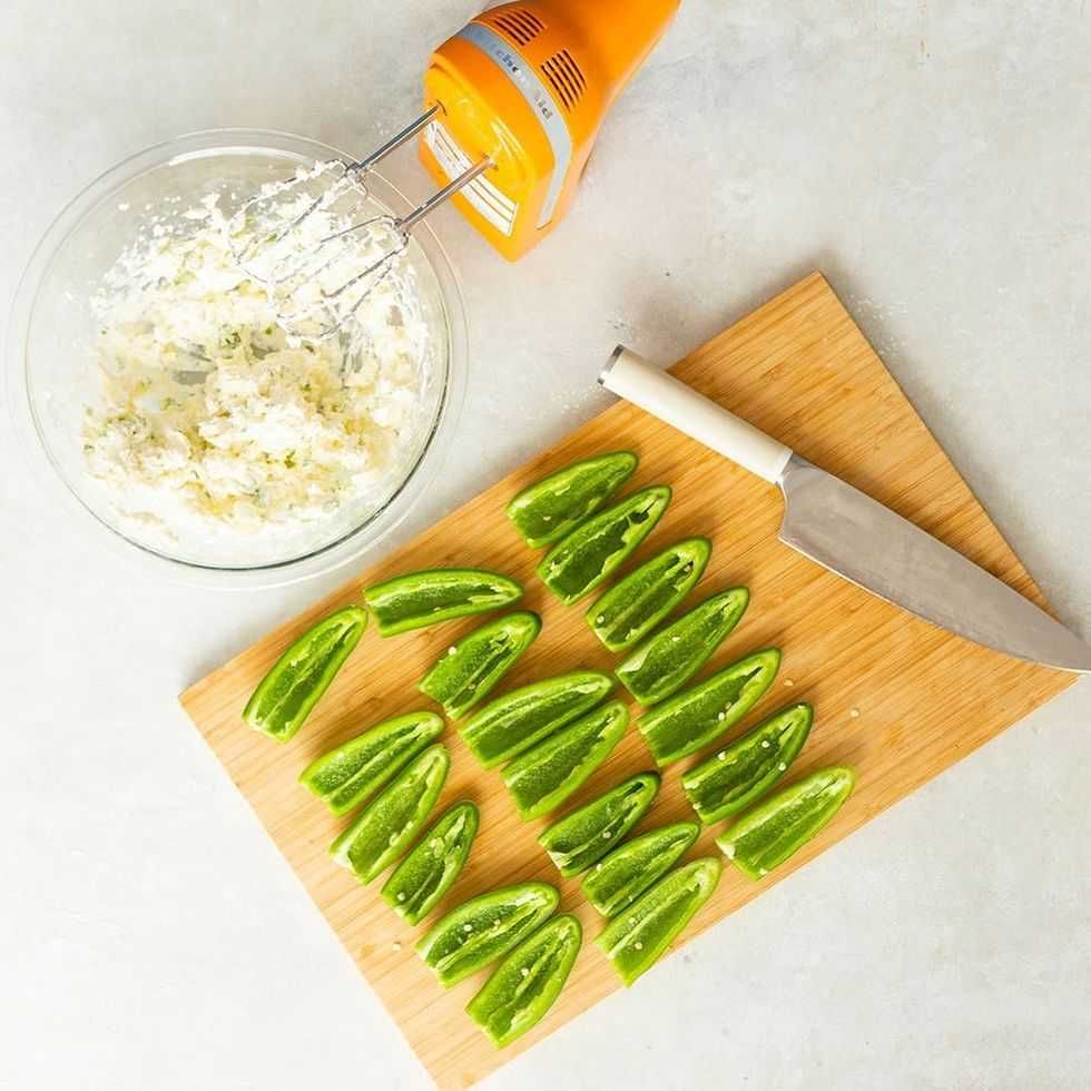 Sliced green peppers on a board with cheese mix and mixer nearby.