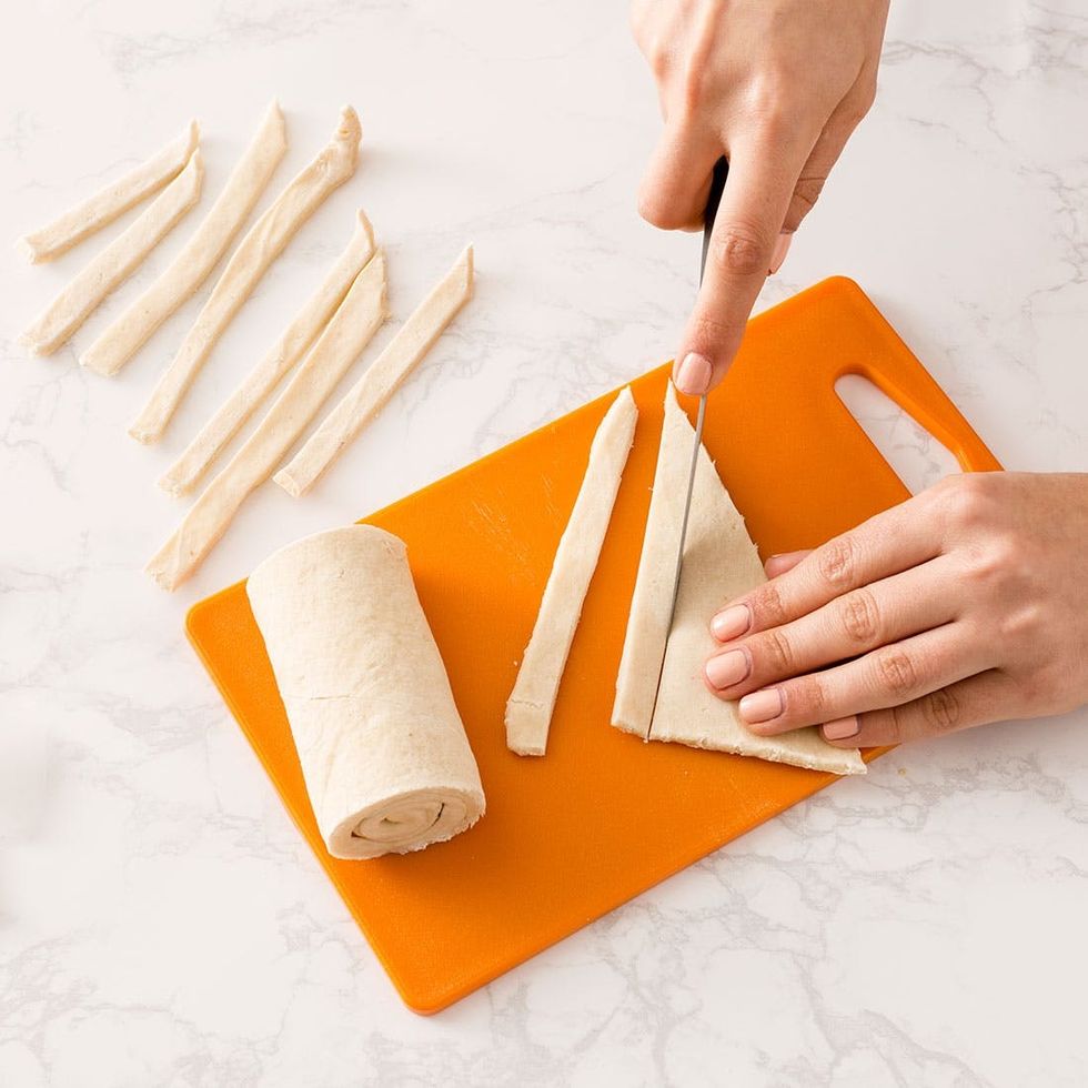 slicing the dough on an orange cutting board