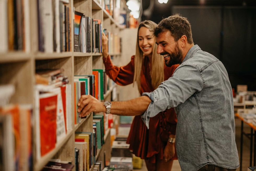 Smiling couple browsing bookshelves in a cozy store.