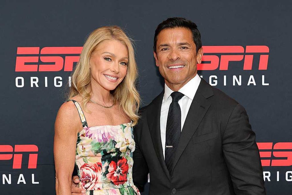 Smiling couple poses at ESPN Originals event, dressed in floral dress and suit.