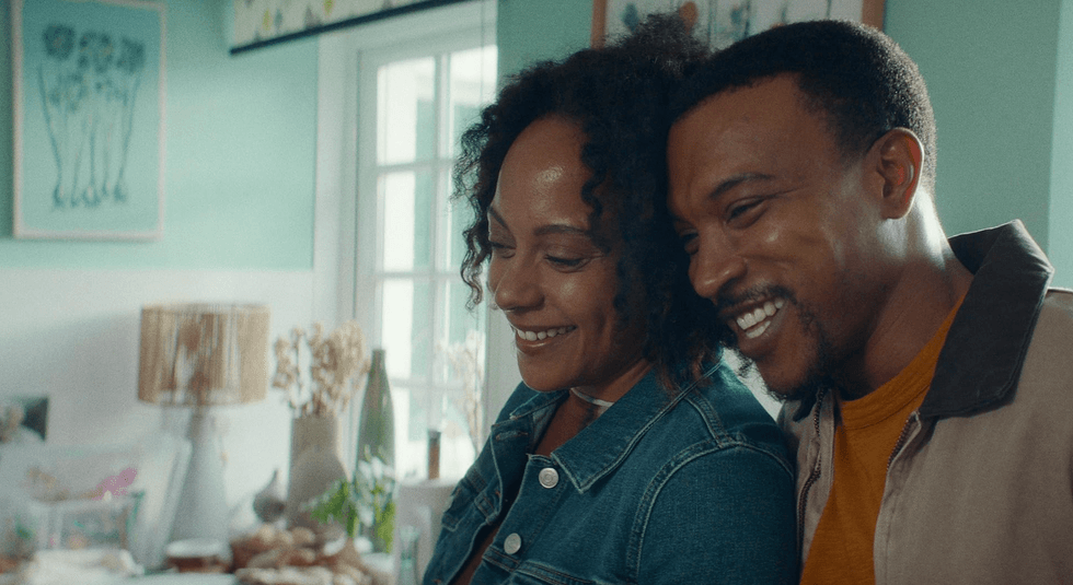 Smiling couple standing close in a cozy, brightly lit room.