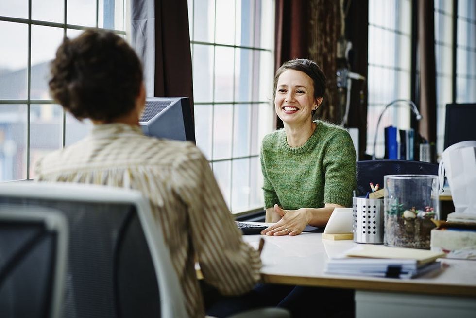 Smiling female business owners in discussion at workstation in office