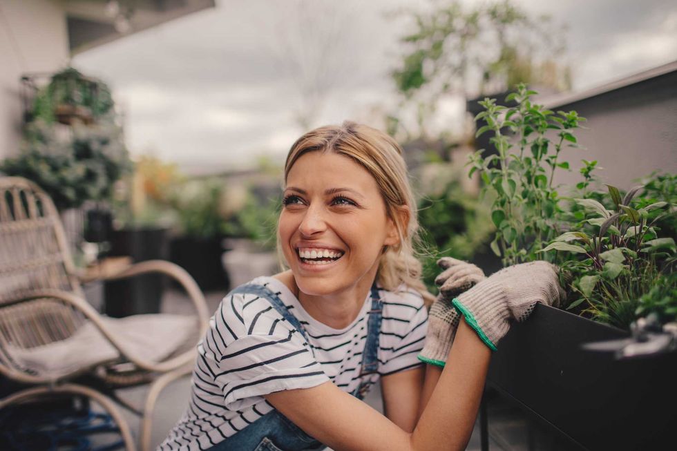 Smiling woman gardening on a balcony.