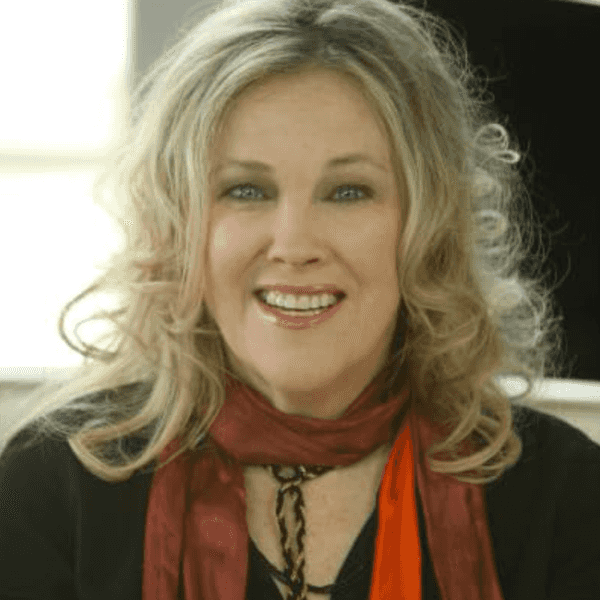 Smiling woman with curly hair, wearing a red scarf and black top.