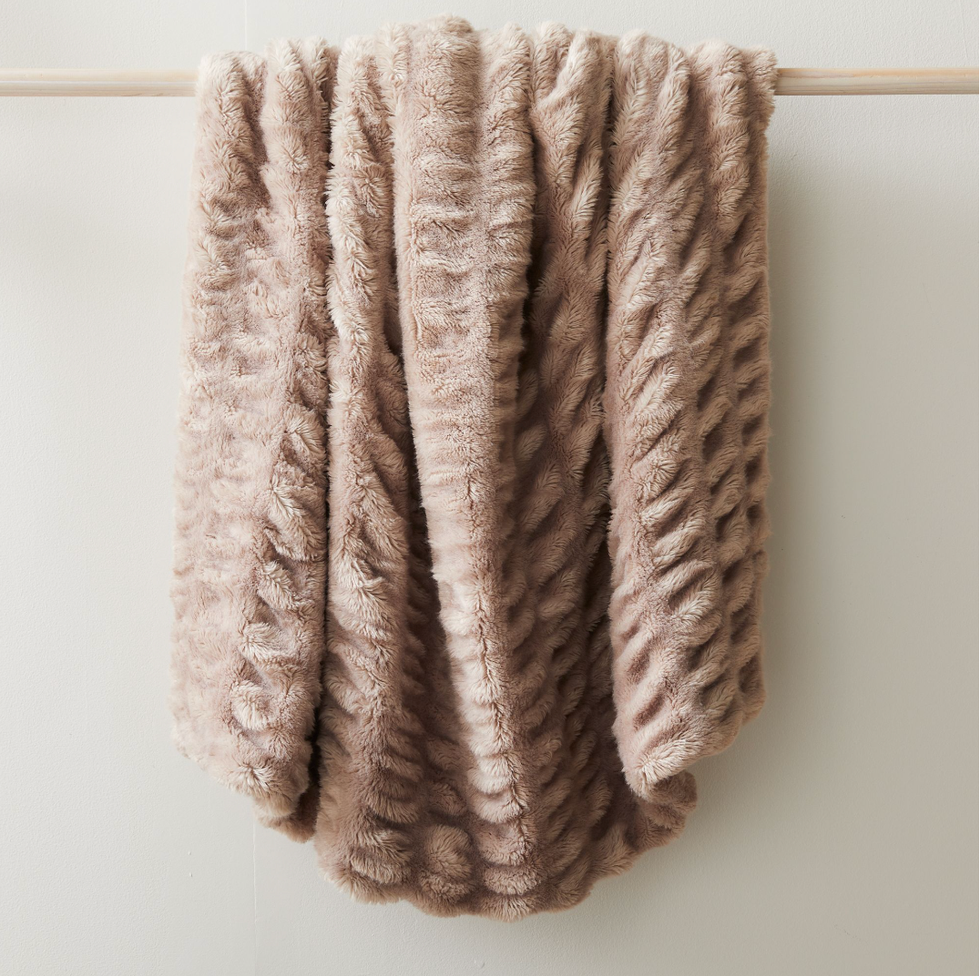 Soft, textured beige plush blanket draped over a wooden rod.