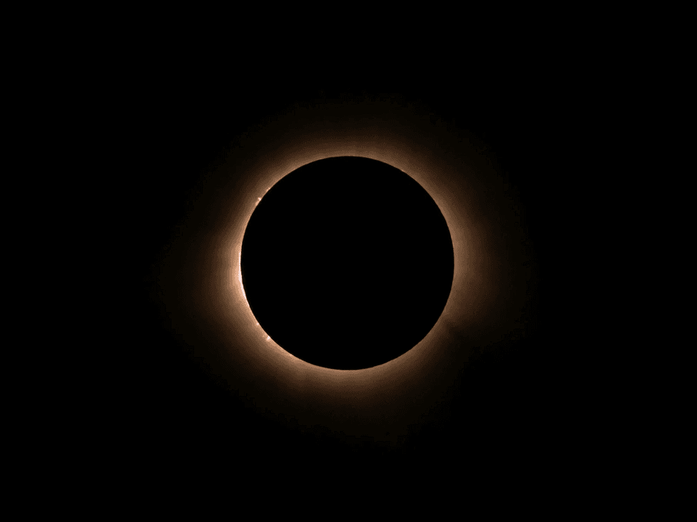 Solar eclipse with a glowing corona against a dark sky.