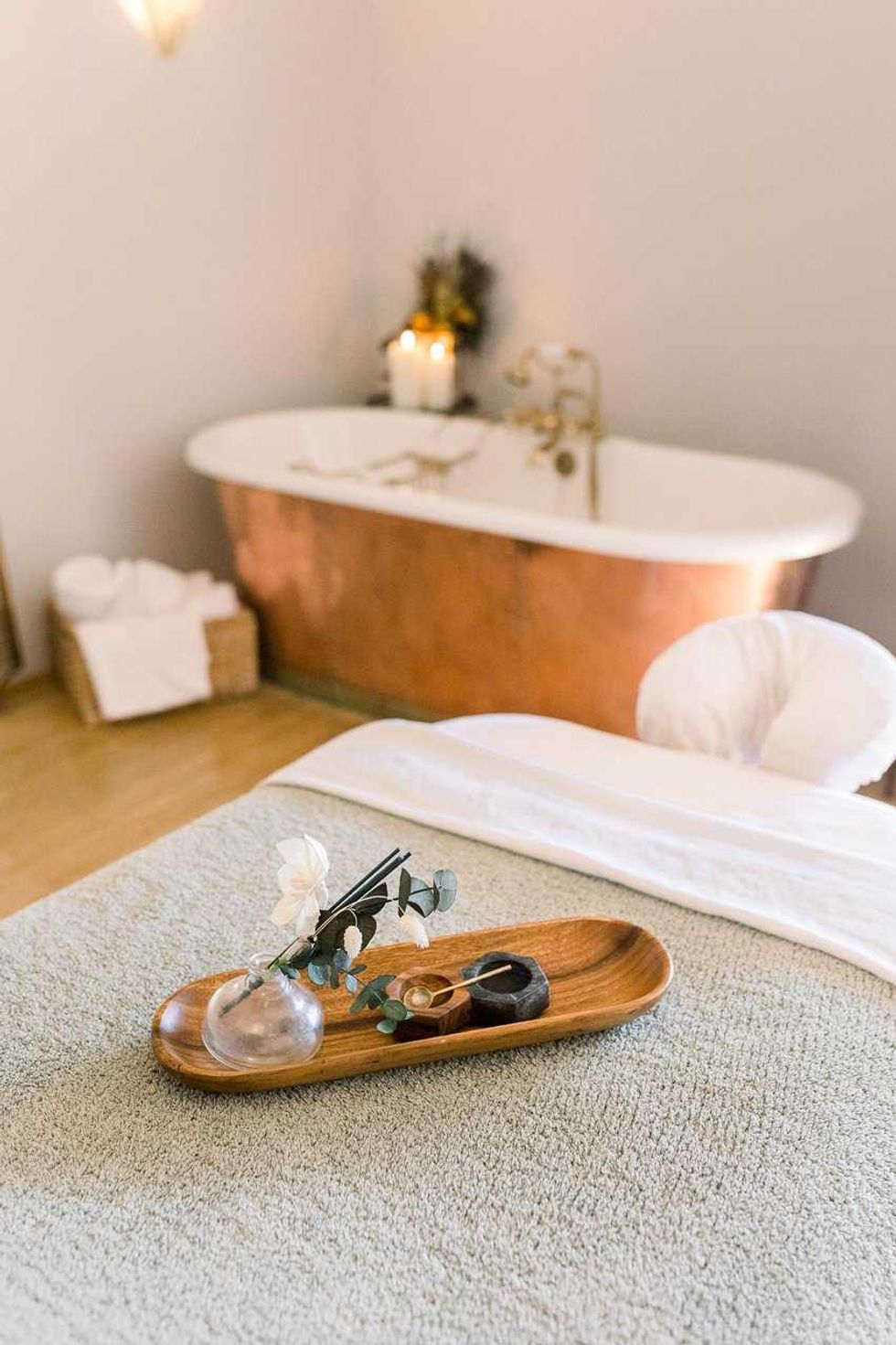 Spa room with copper bathtub, massage table, and decorative tray.