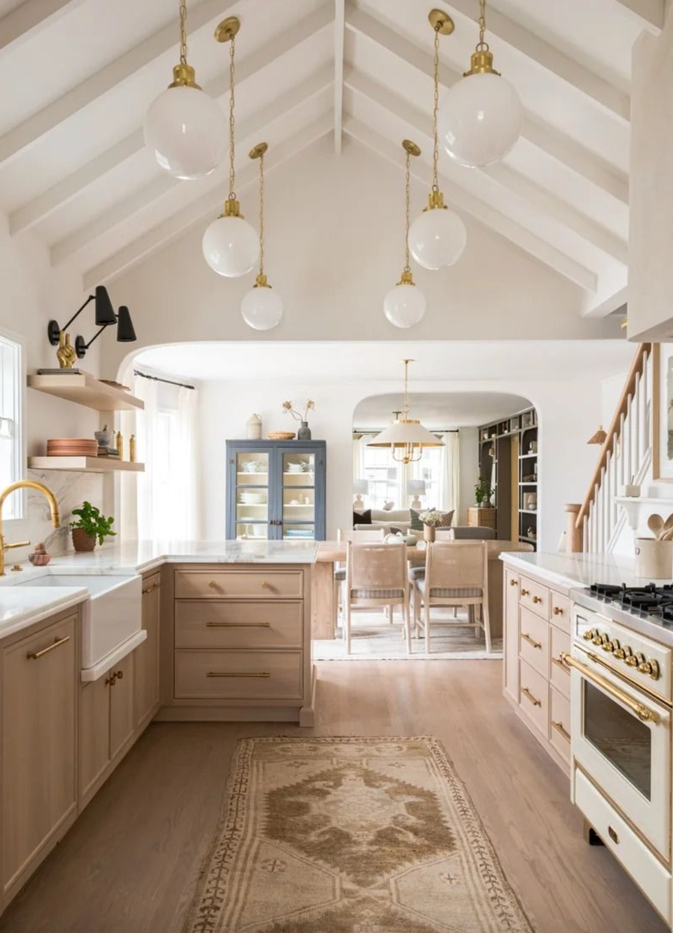 Spacious kitchen with vaulted ceiling, globe lights, and light wood cabinetry.