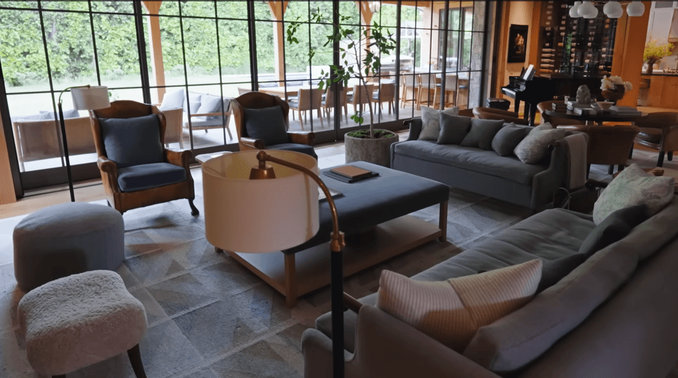 Spacious living room with sofas, armchairs, and large windows overlooking a patio.