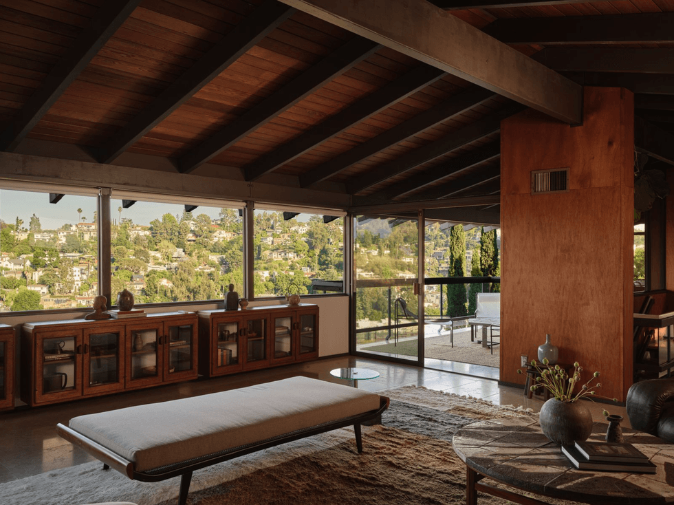 Spacious living room with wooden ceiling and large windows overlooking a scenic hillside view.