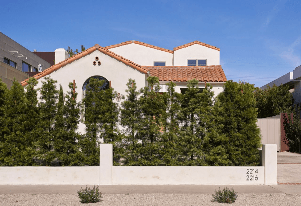 Spanish-style house with trees in front and a terracotta roof.
