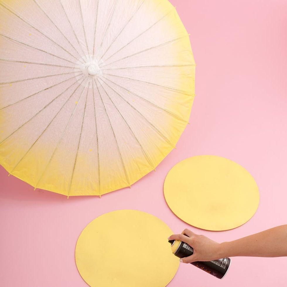 spray painting wood circles for the DIY Ice Cream Cart