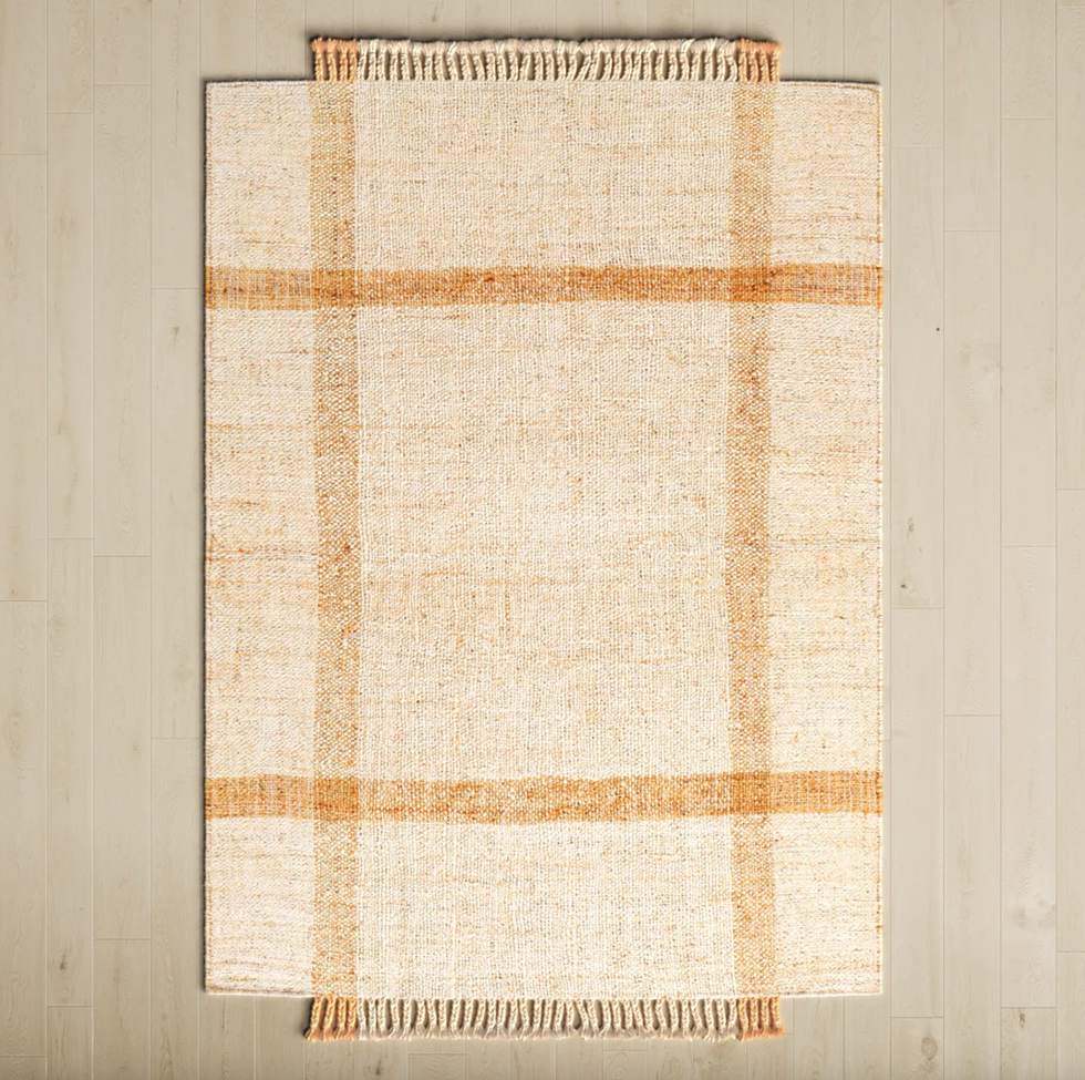Square rug with a beige and brown plaid pattern on a light wooden floor.