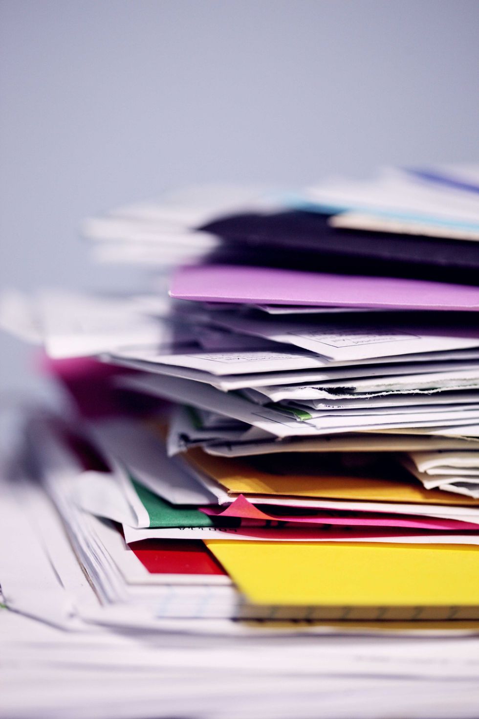 Stack of colorful papers and folders on a desk.