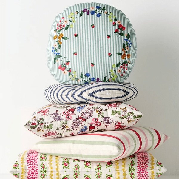 Stack of five floral and striped decorative cushions on a white background.