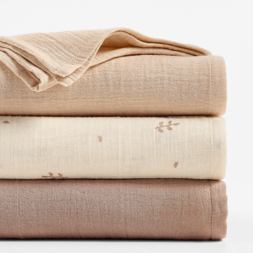 Stack of three folded beige and cream textiles with subtle patterns.