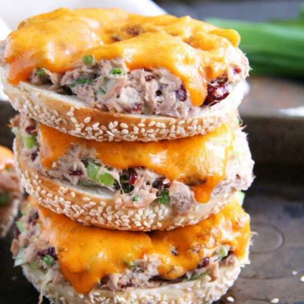 Stacked bagel halves with tuna salad and melted cheddar cheese.