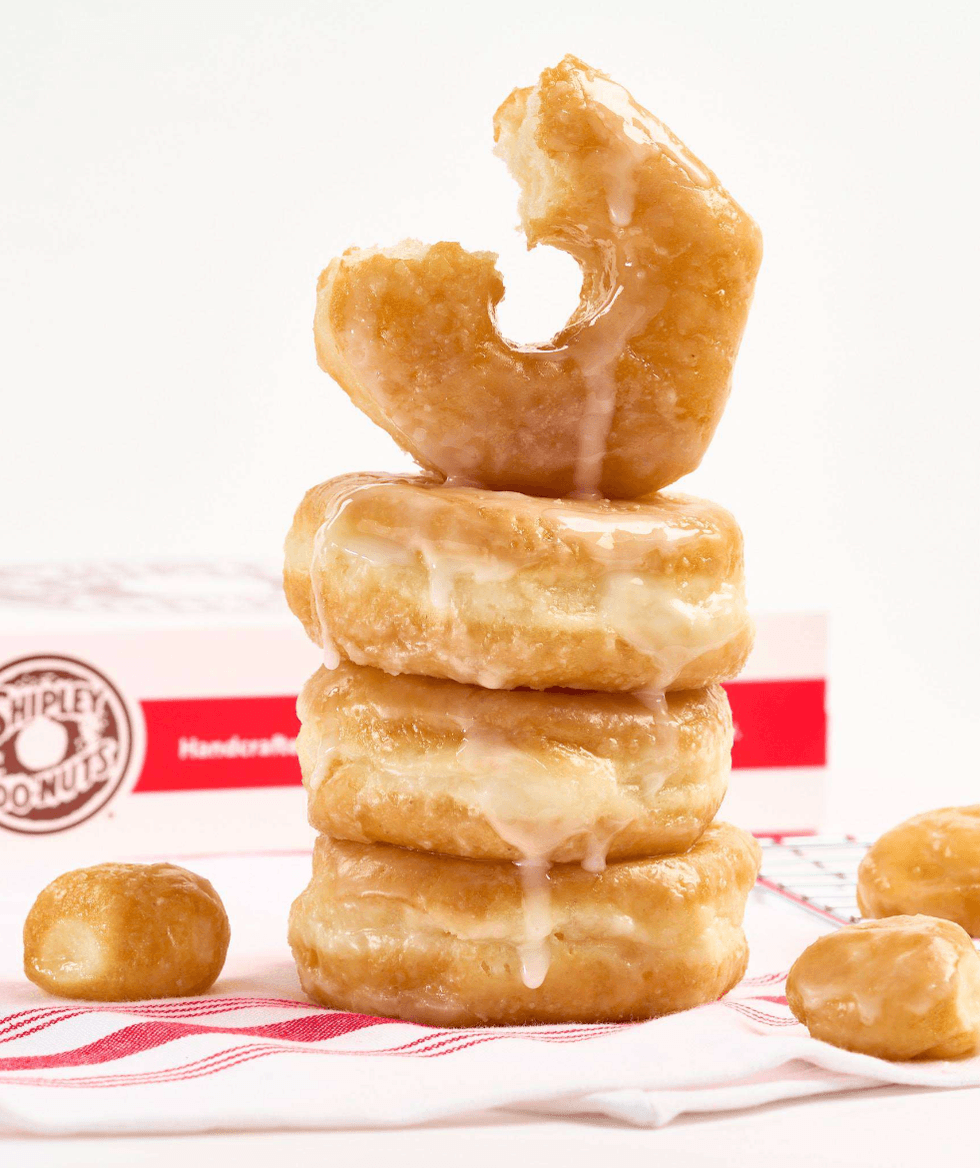 Stacked glazed donuts with a bite taken from the top one.
