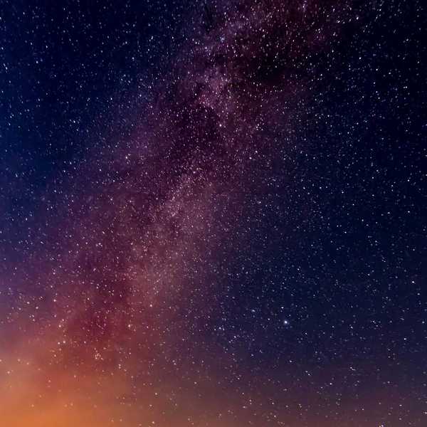 Starry night sky with Milky Way and colorful horizon.