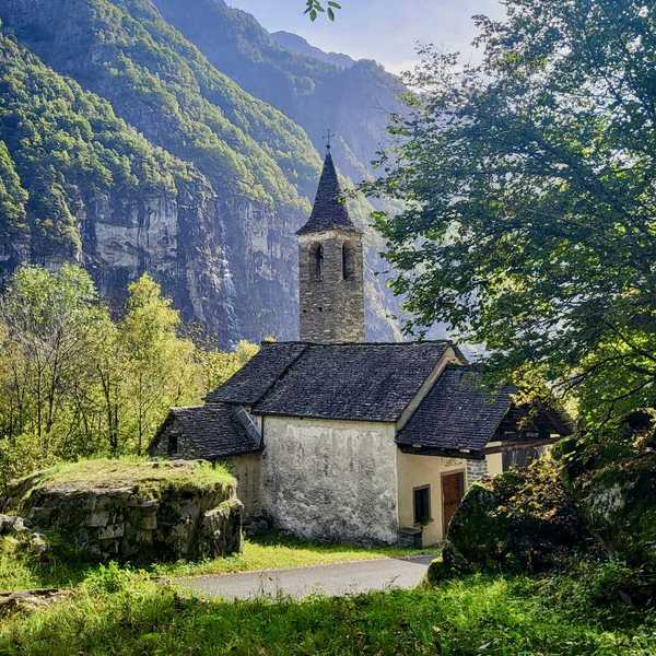 Stone church with tower in lush mountain landscape.