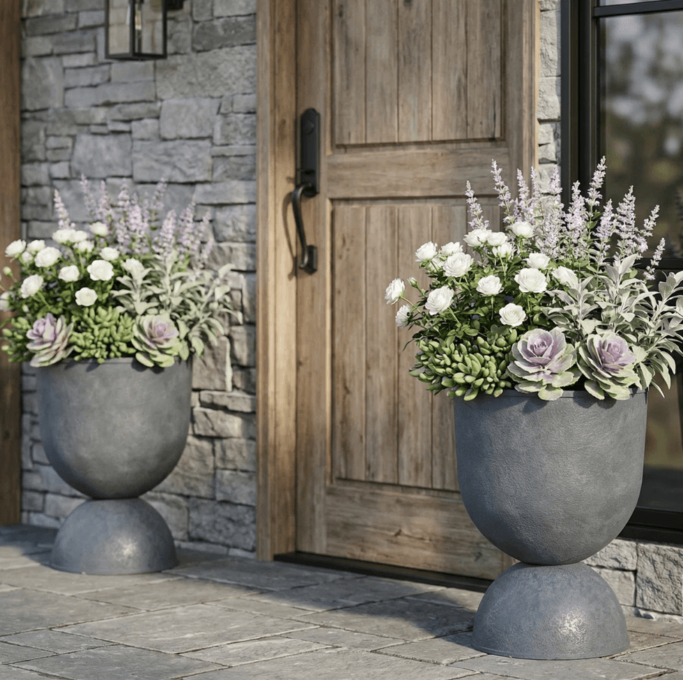 Stone planters with flowers by a wooden door on a stone patio.