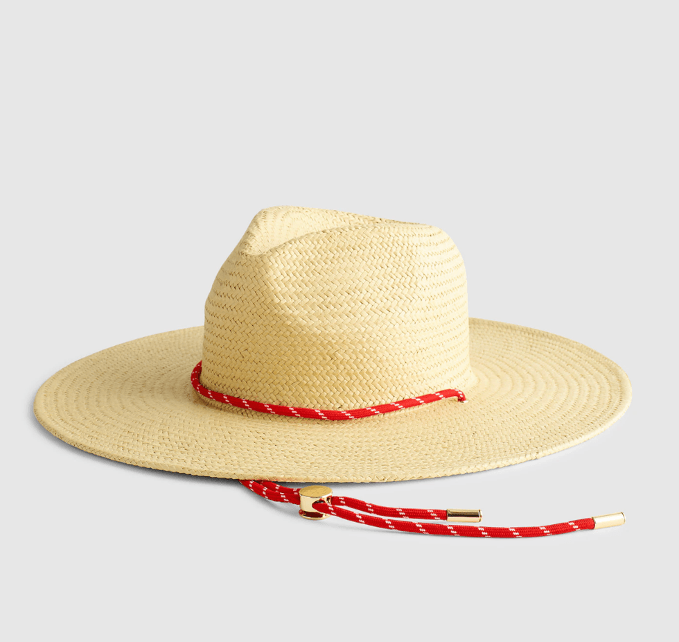 Straw hat with a wide brim and a red braided cord on a white background.
