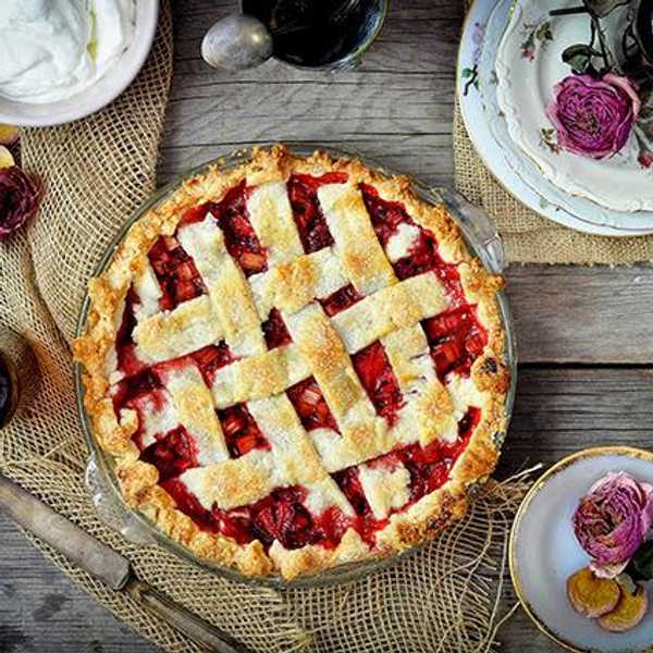 strawberry rhubarb pie with a lattice top and rose whipped cream