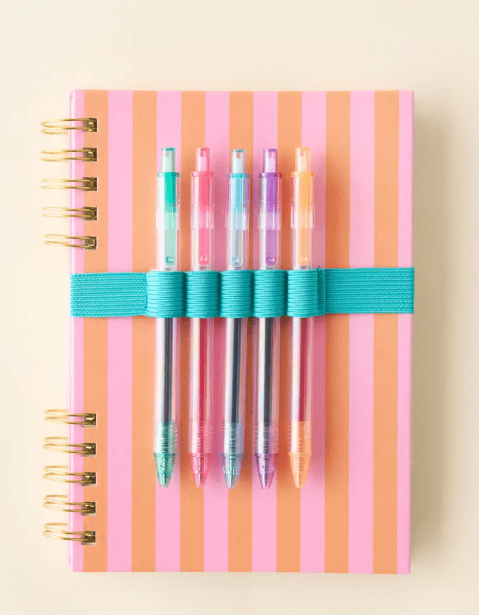 Striped notebook with colorful pens held by a teal band.
