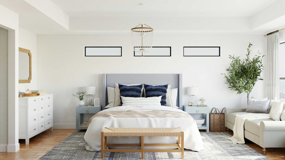 Stylish bedroom with a gray bed, white walls, and a potted plant by the window.