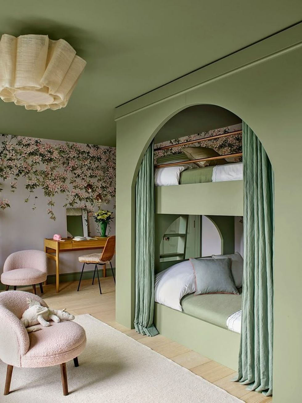 Stylish green room with bunk beds, floral wallpaper, and cozy seating area.