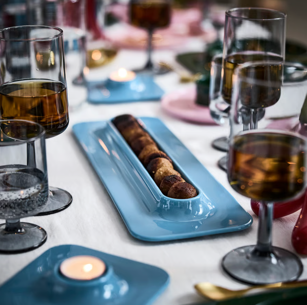 Table setting with glasses, a blue tray of pastries, and lit candles.
