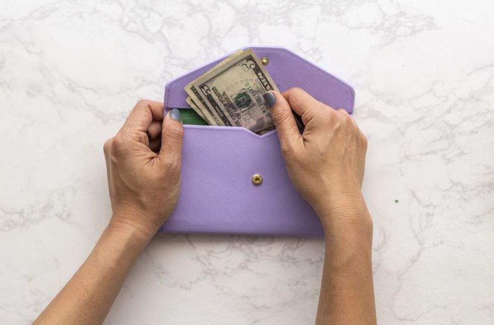 taking money out of a lavender wallet