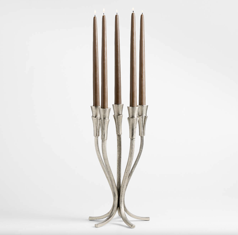 Tall silver candelabra with four lit brown taper candles.