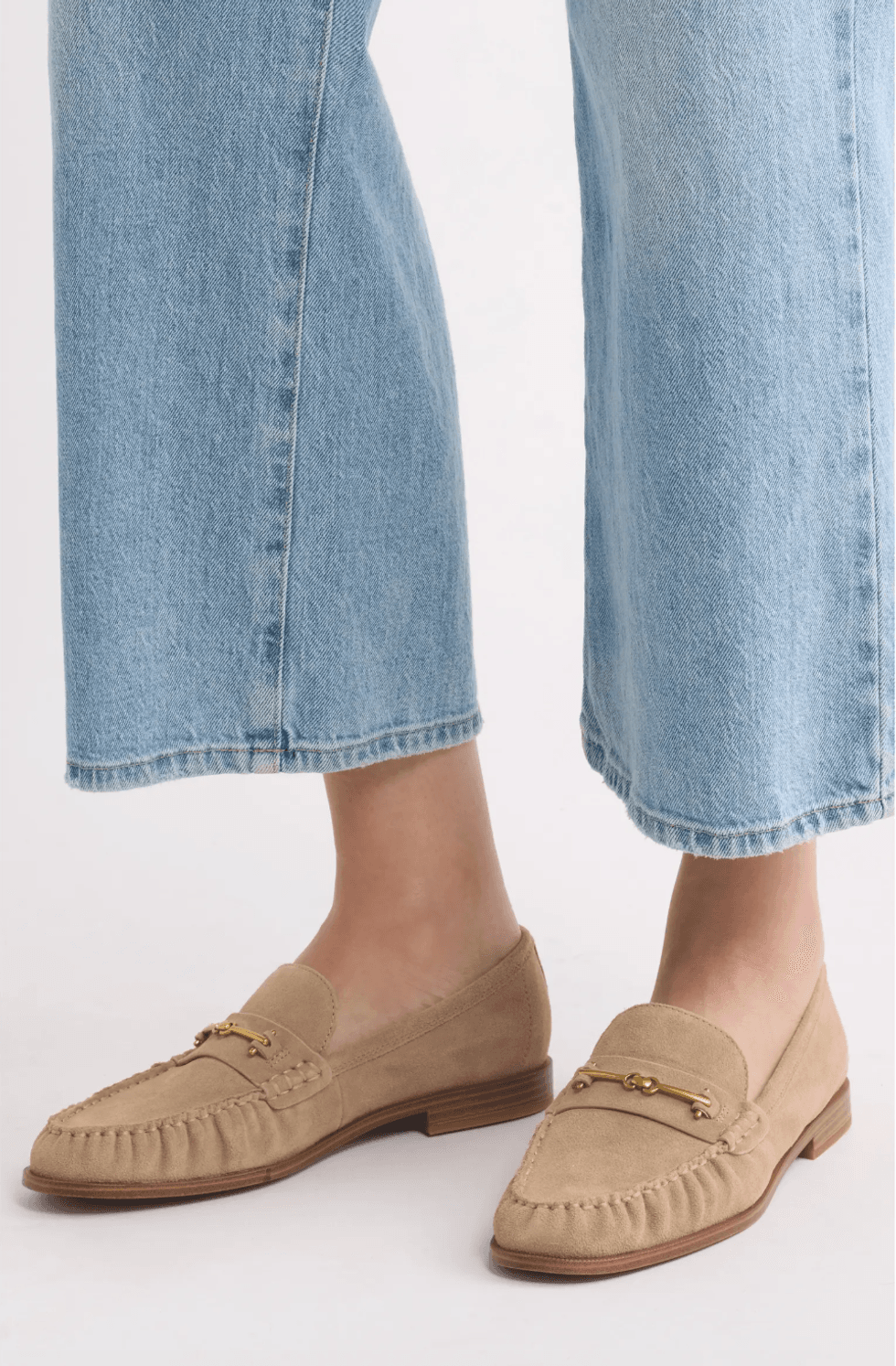 Tan loafers with gold detailing, paired with light blue jeans.
