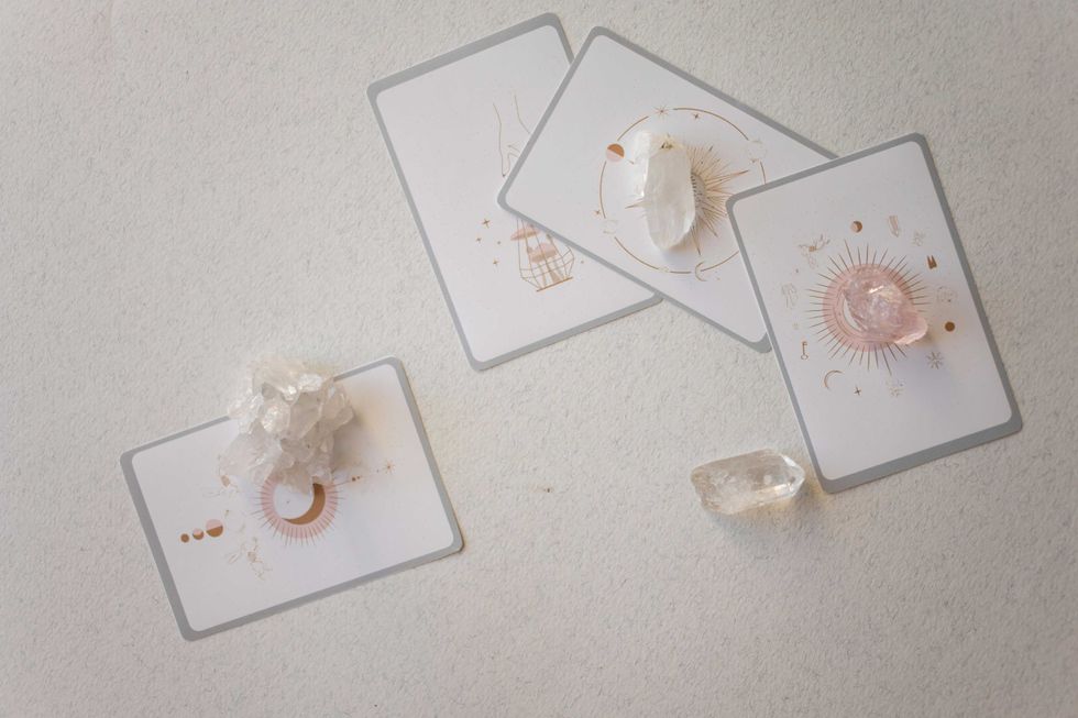 Tarot cards with crystals on a soft white surface.