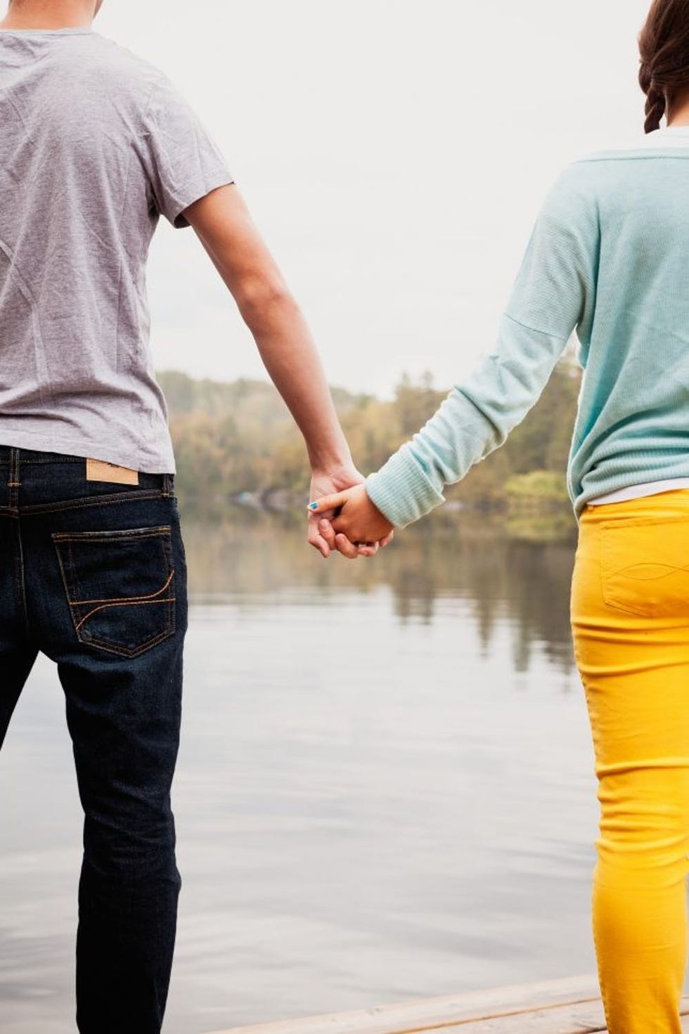 Teen couple holding hands by a lake