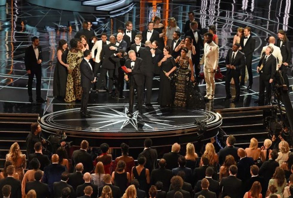 The cast of "Moonlight" and ""La La Land" appear on stage as presenter Warren Beatty (C), flanked by host Jimmy Kimmel (L) shows the winner's envelope for Best Movie "Moonlight" on stage at the 89th Oscars on February 26, 2017 in Hollywood, California. / AFP / Mark RALSTON (Photo credit should read MARK RALSTON/AFP/Getty Images)