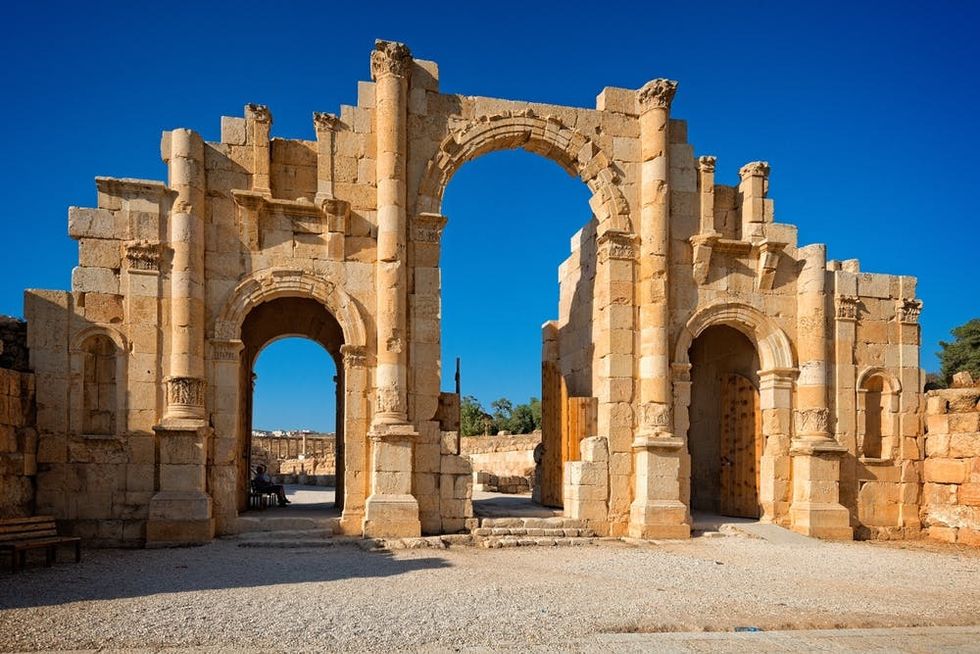 The city of Jerash's ancient South Gate stands against a bright blue sky