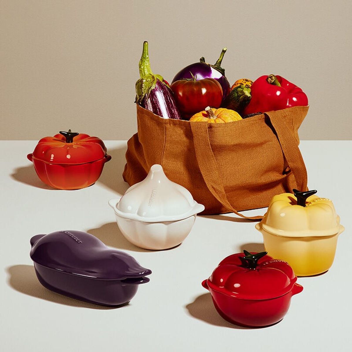 the le creuset fall harvest collection features fruit and vegetable-shaped casserole dishes