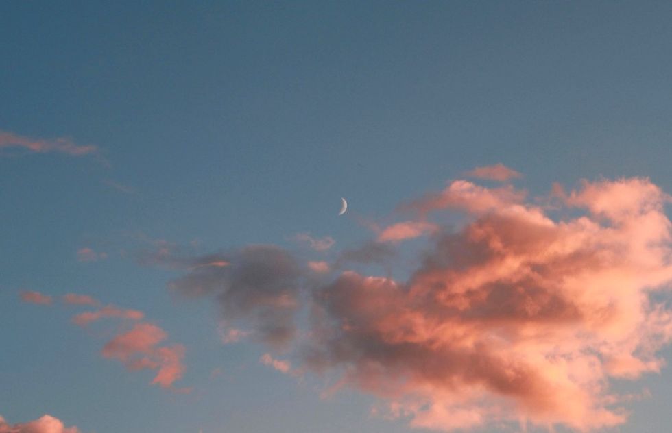 the moon in a blue sky with pink clouds