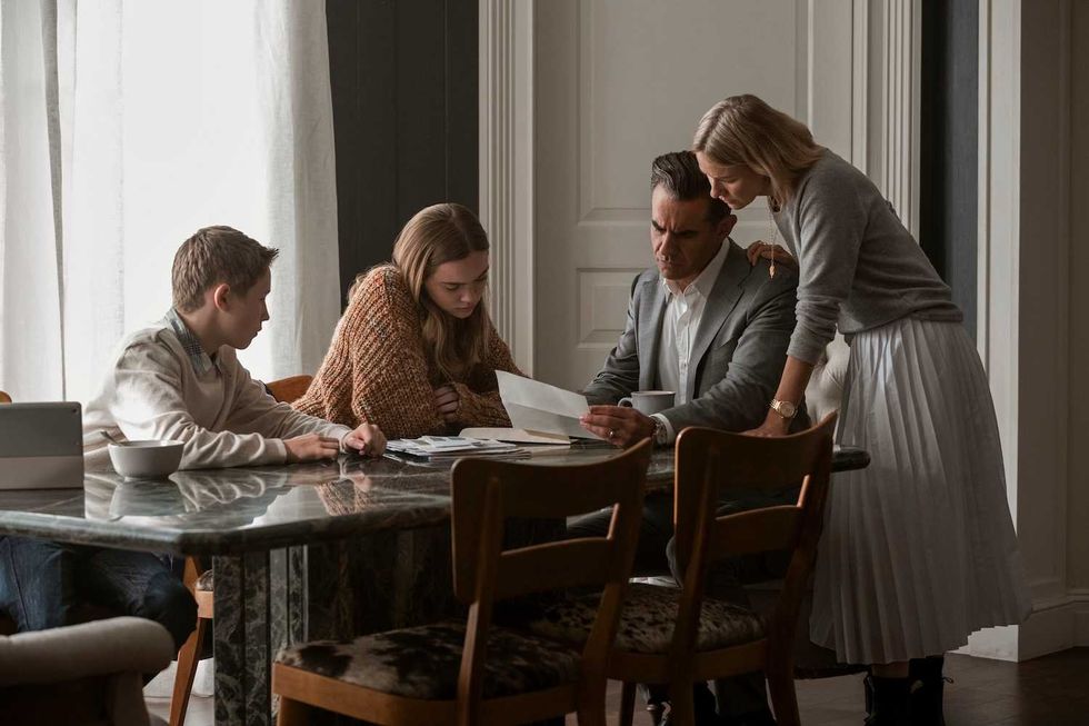 the watcher cast sitting at a table reading a letter